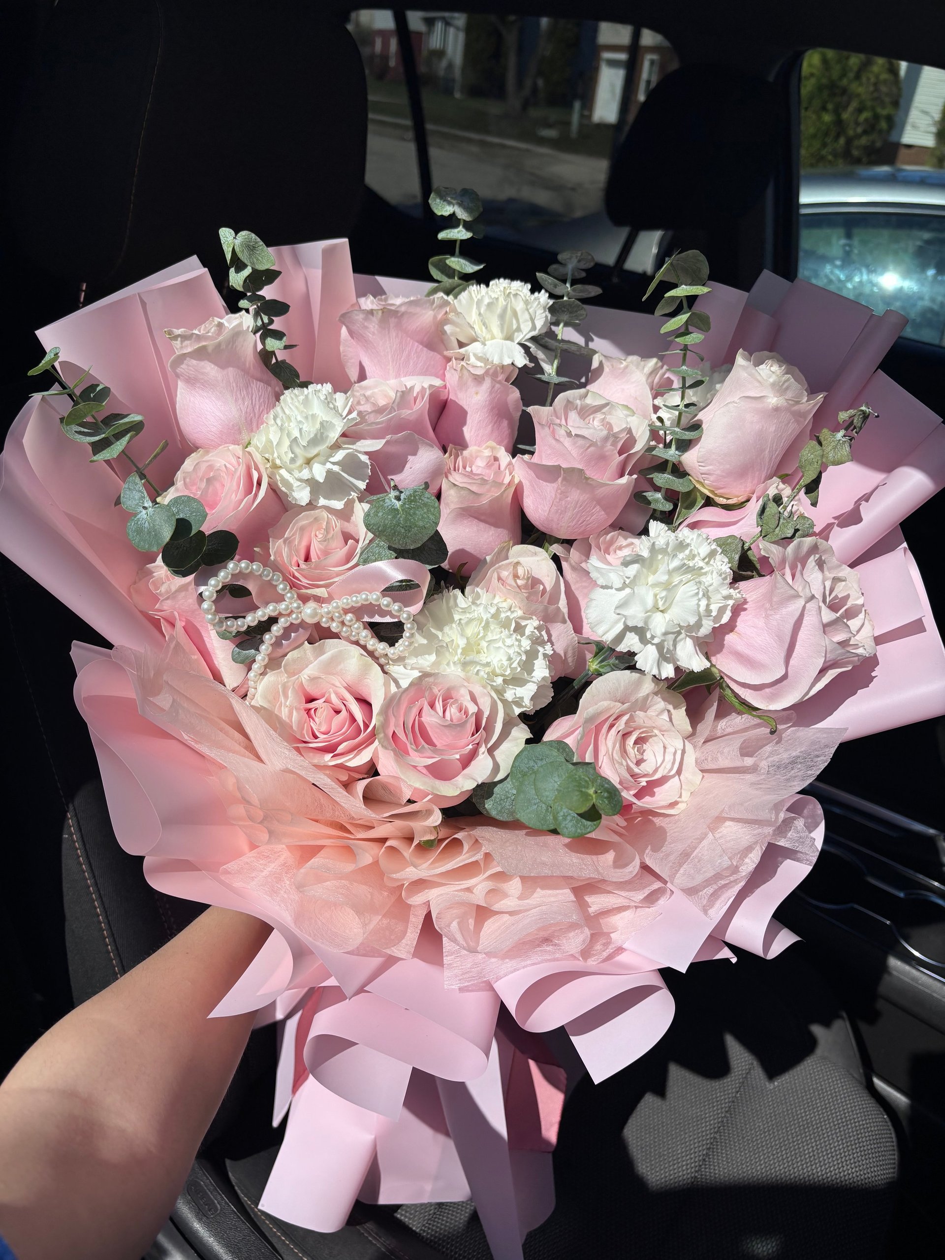 Person holding a large bouquet of pink and white roses