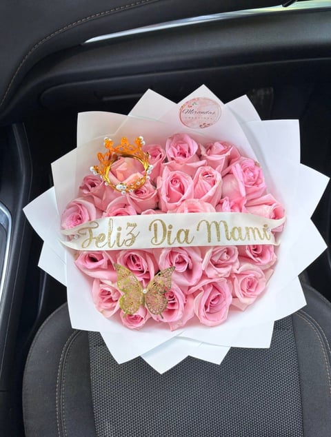 Luxury flower bouquet with pink roses and gold Feliz Dia Mami banner, placed in car seat