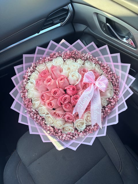 Heart-shaped floral bouquet with pink and white roses and babys breath on a car seat